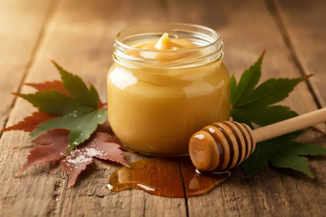 maple butter in a jar on a wooden table , maple leafs next to it and honey dip